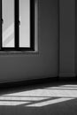 Side view of sunlight shining through the glass window onto tile floor in empty room at home in black and white style and vertical