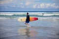 Side view of surfer holding surfboard and walking in water Royalty Free Stock Photo