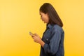 Side view of surprised girl in stylish denim shirt typing message and expressing shock, dialing number calling Royalty Free Stock Photo