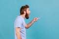 Side view of shocked bearded man pointing aside, showing blank copy space for idea presentation. Royalty Free Stock Photo