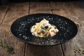 Tagliatelle with spinach and salmon in a black plate on the wooden table Royalty Free Stock Photo