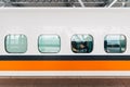 Side view of Taiwan High Speed Train, White train with orange and blue stripe with passengers sitting near window stop on platform