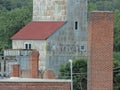 Side view of a tall cement silo situated beside two brick pillars and a small chapel Royalty Free Stock Photo