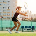 Side view of a teenage girl returning the tennis ball. Sunlit