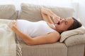 Tired pregnant woman yawning with her hand to mouth