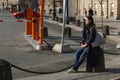 Side view of tired woman in black coat sitting at sidewalk