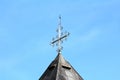Side view of top of local country church roof covered with old metal roof tiles and unusual shiny metal cross