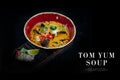 Side view of traditional Thai Tom Yum seafood soup served in bowl isolated on black background. Ready advertising banner with text Royalty Free Stock Photo