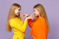 Side view of two funny blonde twins sisters girls in colorful clothes putting fingers on nose having fun  on Royalty Free Stock Photo