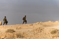 Side view of two infantry men with weapons in walking in desert in a hot sunny day against blue sky. Two figures of soldiers Royalty Free Stock Photo