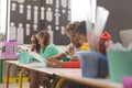 Side view of two mixed-race school boys looking at their notebook in classroom at school