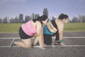 Two obese women kneeling on the track