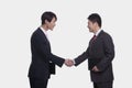 Side view of two smiling businessmen shaking hands, studio shot Royalty Free Stock Photo