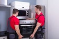 Young Male Worker Placing Modern Oven In Kitchen