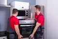 Young Male Worker Placing Modern Oven In Kitchen Royalty Free Stock Photo