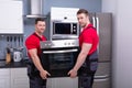 Young Male Worker Placing Modern Oven In Kitchen