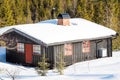 Side view of a typical black Norwegian cabin covered in snow