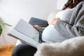 Unrecognizable pregnant woman looking at photo album Royalty Free Stock Photo