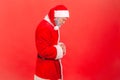 Side view upset disappointed man in santa claus costume standing alone, frustrated worried about holidays