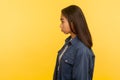 Side view of upset girl in denim shirt standing with unhappy gloomy expression, feeling annoyed and dissatisfied