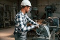 Side view. Using machine. Factory male worker in uniform is indoors