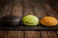 Side view of variety of three hamburger buns on wooden table. Black, green, yellow buns