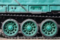 Side view of the vehicle on a caterpillar track with black tracks and green wheels and a side metal wal Royalty Free Stock Photo