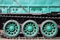 Side view of the vehicle on a caterpillar track with black tracks and green wheels and a side metal wal Royalty Free Stock Photo