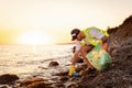 Side view of volunteer Caucasian man wearing vest and rubber gloves picking up garbage. Copy space. Concept of ocean