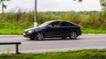 Side view Volvo S40 second generation moving on rural asphalt road. Driver in old black car riding on the village road on high