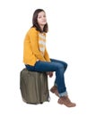 Side view of walking woman in cardigan sits on a suitcase. Royalty Free Stock Photo