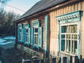 Side view of the wall of an old wooden house with windows and blue shutters Royalty Free Stock Photo