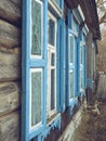 Side view of the wall of an old wooden house with windows and blue shutters. Selective Focus Royalty Free Stock Photo