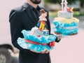 The side view of the wedding cake with decorations carried by the man. Royalty Free Stock Photo