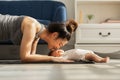Side view of Wellness Asian woman mom doing plank exercise and kissing her baby at cozy home.Happy healthy mother yoga plank with Royalty Free Stock Photo