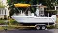 Side view of white boat on trailer moored on residential neighborhood street Royalty Free Stock Photo