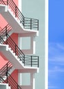 Side view of white fire escape outside of colorful pastel apartment building with blue sky background in vertical frame Royalty Free Stock Photo