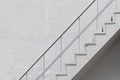 Side view of white outside fire escape emergency staircase with metal handrail railing and concrete wall Royalty Free Stock Photo