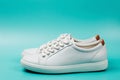 Side view of white trendy sneakers on turquoise background