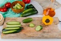 side view of whole sliced and cut cucumbers and black pepper on cutting board with tomatoes melted oil bowl of cucumber slices and Royalty Free Stock Photo