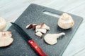 side view of whole and sliced fresh mushrooms with kitchen knife on a black cutting board on rustic background Royalty Free Stock Photo