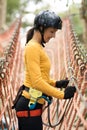 Woman attaching carabiner to rope bridge