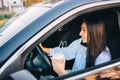 Happy young woman with coffee to go driving her car. Royalty Free Stock Photo