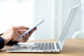 Side view of woman hands using mobile phone while working in the office with laptop. Blurred background. Texting Royalty Free Stock Photo