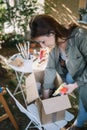 Side view of woman holding paint tubes in yard Royalty Free Stock Photo