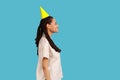 Side view of woman in party cone hat, looking at camera with toothy smile, rejoicing celebration. Royalty Free Stock Photo