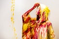 side view of woman in raincoat painted with yellow and red paints taking off hood Royalty Free Stock Photo