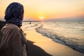 Side view Woman standing on beach alone on sunset looking at seascape landscape. Sunset light, golden hour. Nature and journey Royalty Free Stock Photo