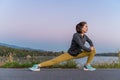 Side view of a woman stretching her legs before her early morning exercise at a local lake park Royalty Free Stock Photo