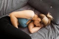 Side view of woman suffering from stomach ache lying on sofa at home Royalty Free Stock Photo